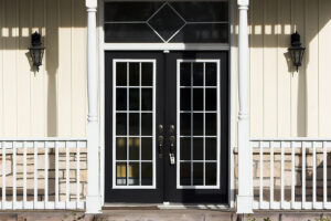 A set of beautiful navy blue French doors installed on a creamy yellow house